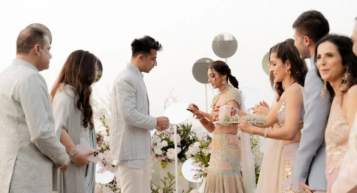 A beautiful outdoor wedding ceremony with traditionally dressed guests exchanging rings.