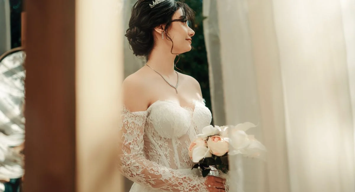 A beautiful bride in lace dress holding a bouquet, standing during her wedding ceremony.