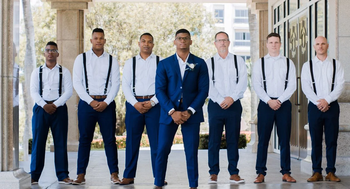 A group of groomsmen posed elegantly outside a wedding venue in matching suits.